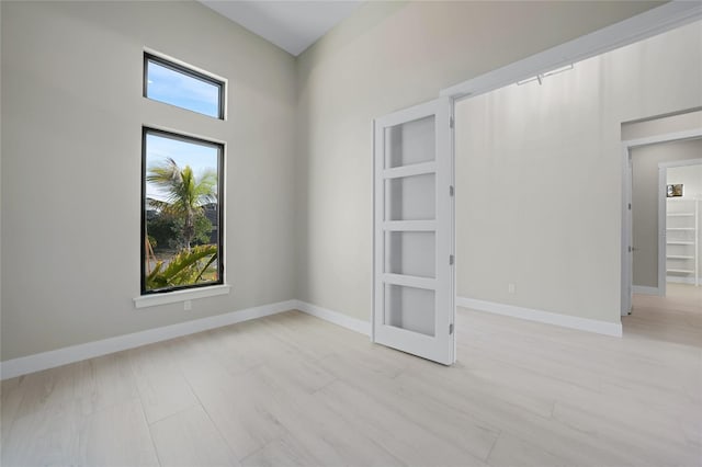 spare room featuring plenty of natural light, built in features, and light hardwood / wood-style flooring