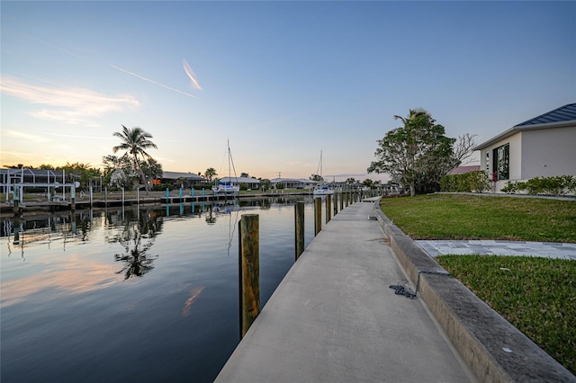 dock area with a lawn and a water view