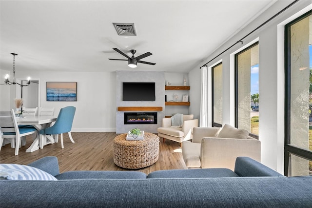 living room with ceiling fan with notable chandelier and hardwood / wood-style floors