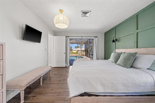 bedroom with access to exterior, dark hardwood / wood-style flooring, and a textured ceiling