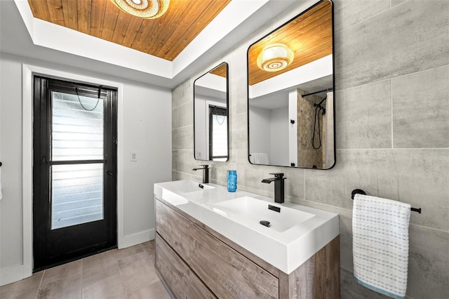 bathroom featuring wood ceiling, tile walls, vanity, a tray ceiling, and backsplash