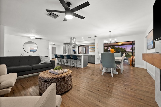 living room with hardwood / wood-style flooring and ceiling fan with notable chandelier