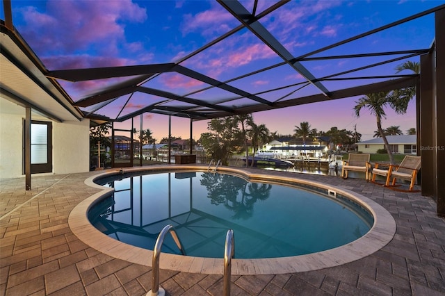 pool at dusk with a lanai and a patio area