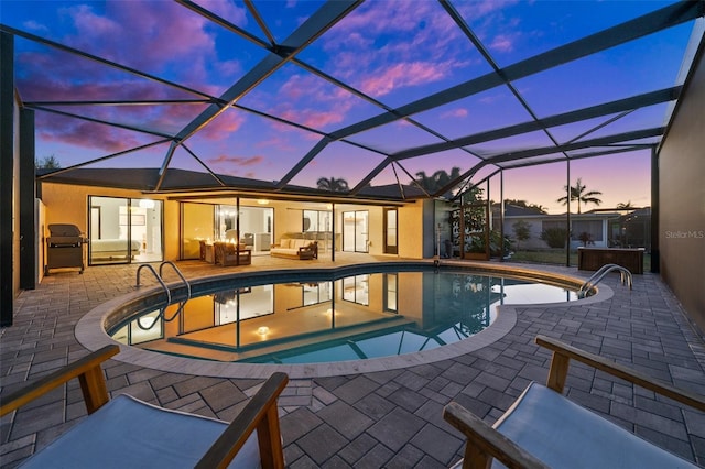 pool at dusk featuring a lanai, outdoor lounge area, a patio, and a hot tub