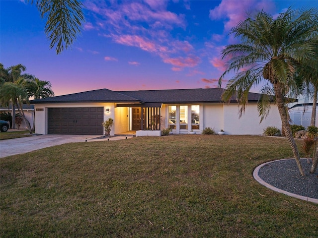 ranch-style home with a garage and a yard