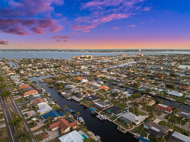 aerial view at dusk featuring a water view