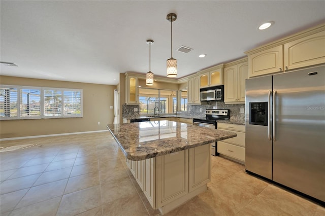 kitchen featuring stone counters, decorative light fixtures, sink, backsplash, and stainless steel appliances