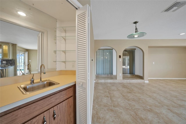 kitchen with light tile patterned flooring, decorative light fixtures, sink, and a textured ceiling