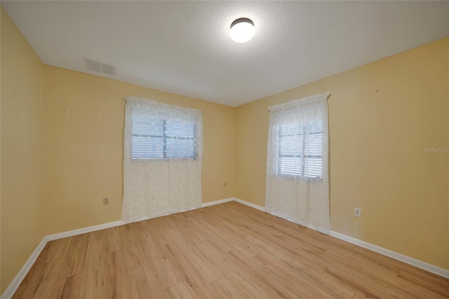 empty room with a textured ceiling and light wood-type flooring