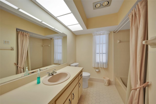 full bathroom with shower / tub combo with curtain, toilet, a skylight, vanity, and tile patterned flooring