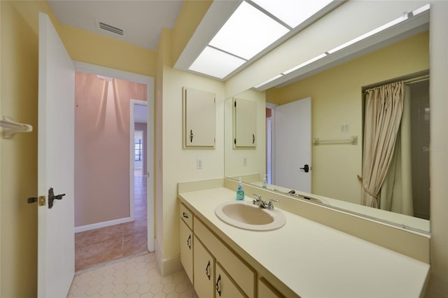 bathroom with tile patterned floors, vanity, and a skylight