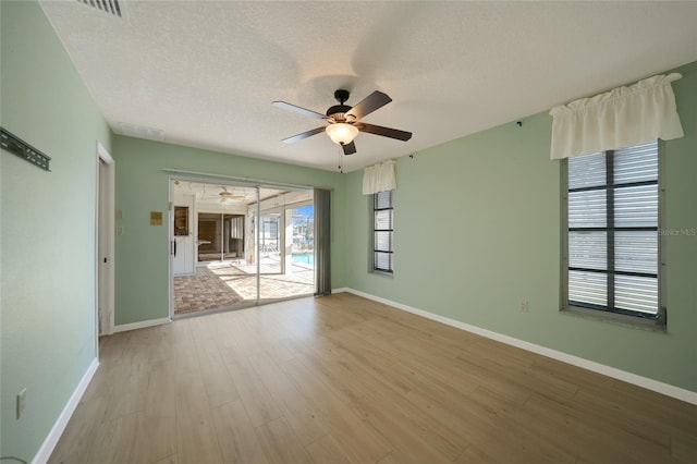 empty room featuring ceiling fan, light hardwood / wood-style floors, and a textured ceiling