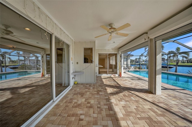 exterior space with a patio, a water view, ceiling fan, and a lanai