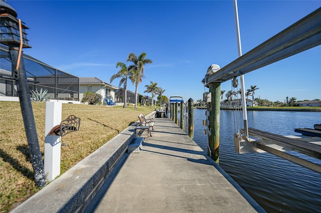 view of dock with a lawn, a water view, and glass enclosure