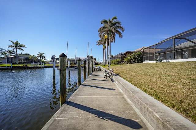 dock area featuring a lanai, a lawn, and a water view