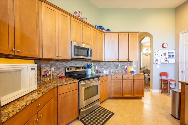 kitchen featuring tasteful backsplash, light tile patterned floors, stainless steel appliances, and dark stone counters