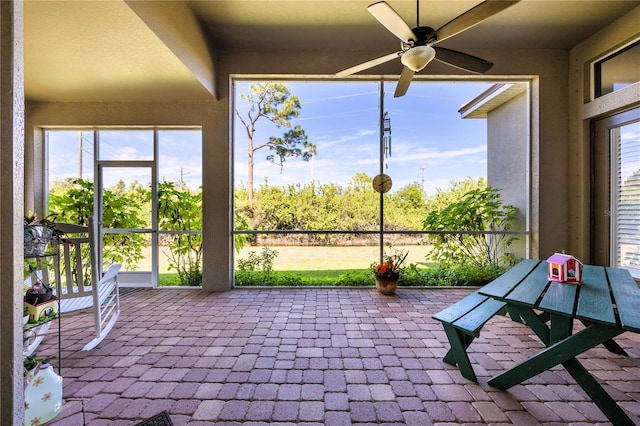 unfurnished sunroom featuring a healthy amount of sunlight and ceiling fan