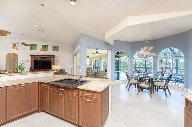 kitchen with pendant lighting, sink, light stone counters, and a healthy amount of sunlight