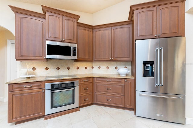 kitchen with light stone counters, tasteful backsplash, stainless steel appliances, and light tile patterned flooring