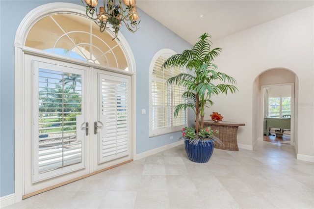 entrance foyer with french doors, a towering ceiling, and an inviting chandelier