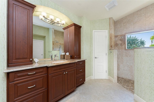 bathroom featuring vanity, vaulted ceiling, tiled shower, and tile patterned floors