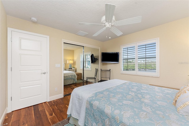 bedroom with ceiling fan, dark hardwood / wood-style floors, a textured ceiling, and a closet