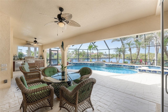 view of swimming pool with ceiling fan, an outdoor kitchen, a lanai, and a patio