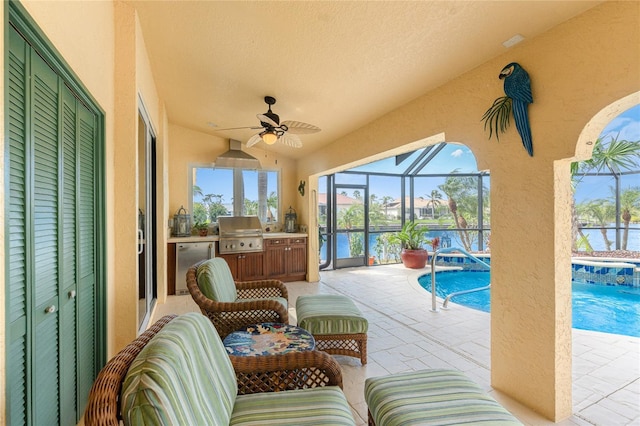 view of patio featuring area for grilling, exterior kitchen, a lanai, ceiling fan, and a water view