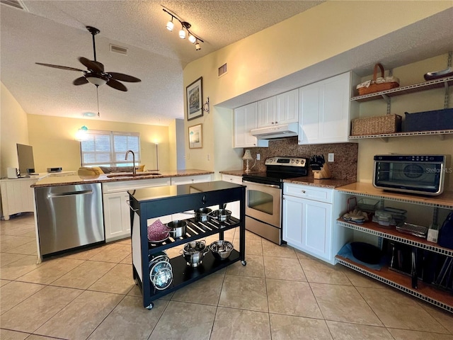 kitchen with lofted ceiling, sink, white cabinetry, light tile patterned floors, and stainless steel appliances