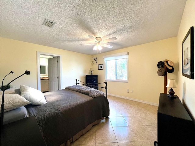 tiled bedroom with a textured ceiling, ceiling fan, and ensuite bath