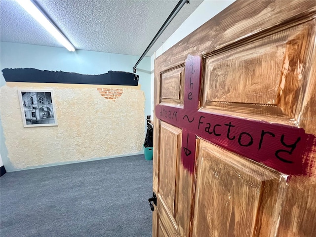 hallway featuring a textured ceiling and dark colored carpet