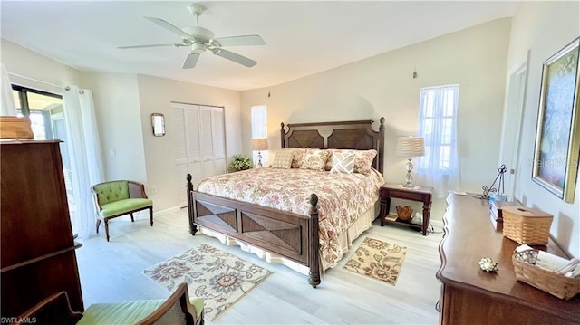 bedroom featuring ceiling fan, a closet, multiple windows, and light wood-type flooring