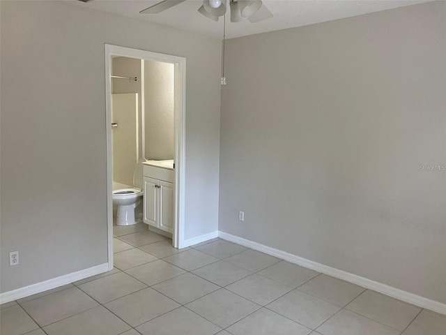 unfurnished bedroom featuring ceiling fan, light tile patterned floors, and ensuite bath