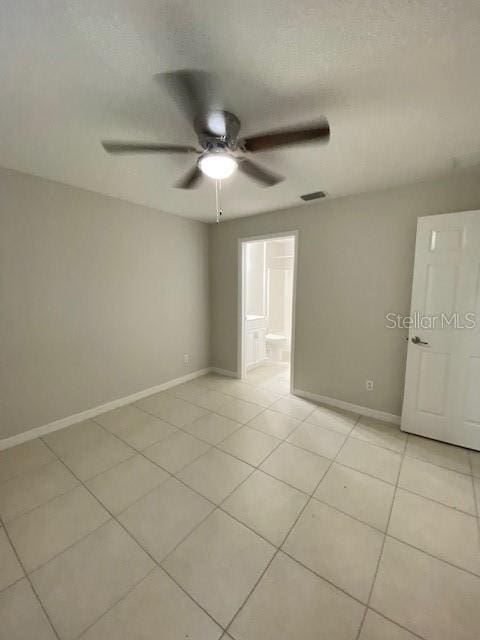 empty room with light tile patterned floors, a textured ceiling, and ceiling fan