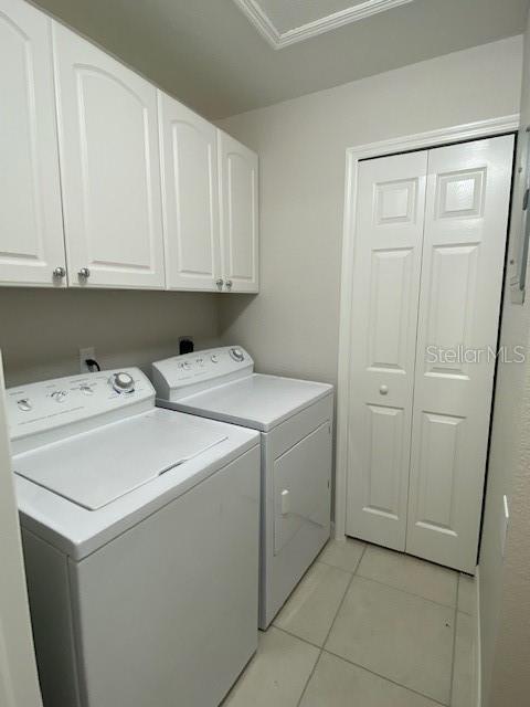 laundry area featuring independent washer and dryer, light tile patterned floors, and cabinets