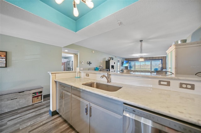 kitchen with sink, pendant lighting, light stone counters, dishwasher, and hardwood / wood-style flooring