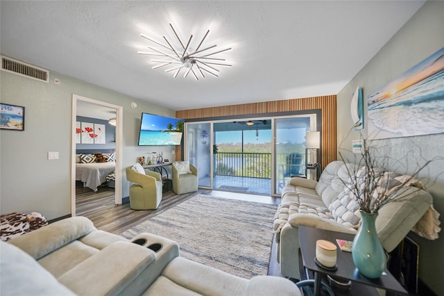 living room with an inviting chandelier, hardwood / wood-style flooring, and a textured ceiling