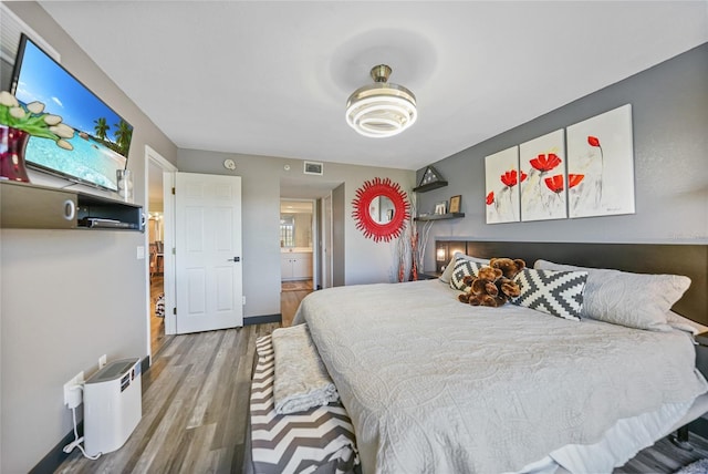 bedroom with hardwood / wood-style floors and ensuite bath