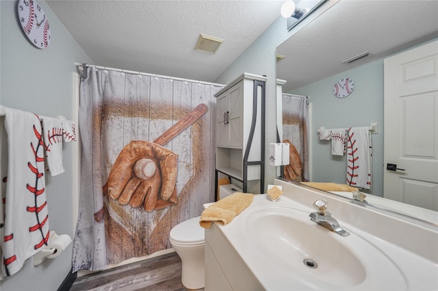 bathroom featuring vanity, a textured ceiling, wood-type flooring, and toilet