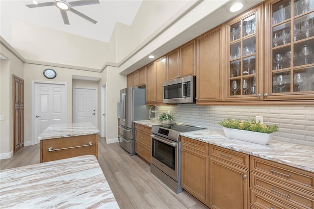 kitchen featuring light stone counters, tasteful backsplash, stainless steel appliances, and light hardwood / wood-style flooring