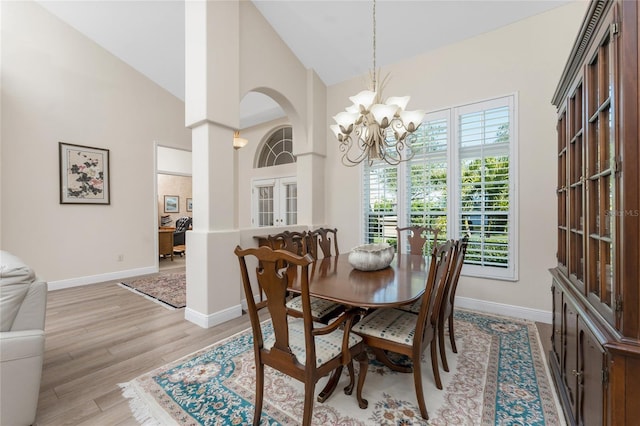 dining space featuring a chandelier, high vaulted ceiling, and light wood-type flooring