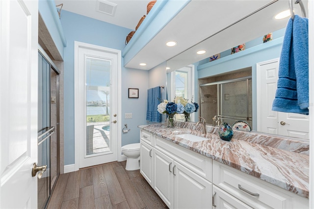 bathroom with vanity, toilet, an enclosed shower, and wood-type flooring