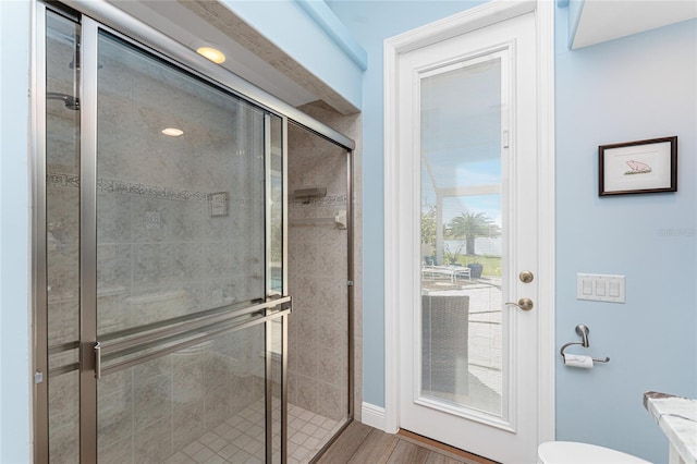 bathroom featuring toilet, wood-type flooring, and a shower with shower door