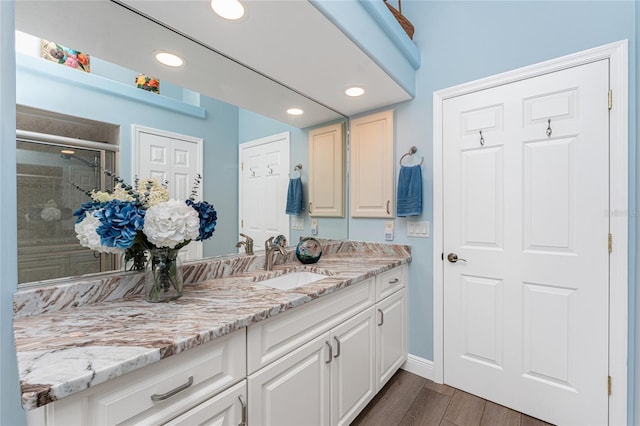 bathroom featuring vanity, hardwood / wood-style flooring, and a shower with door