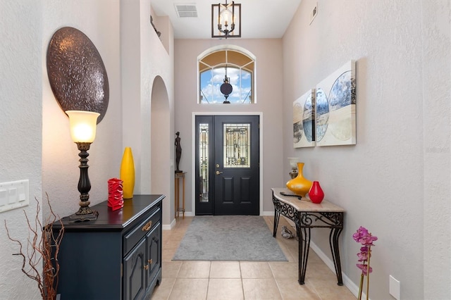 entryway with a high ceiling and light tile patterned flooring