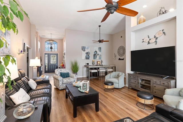 living room featuring ceiling fan, a towering ceiling, and light wood-type flooring