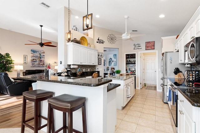 kitchen featuring ceiling fan, appliances with stainless steel finishes, dark stone counters, and white cabinets