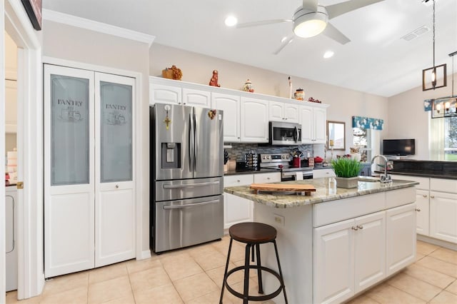 kitchen featuring white cabinetry, decorative light fixtures, a center island, dark stone counters, and stainless steel appliances