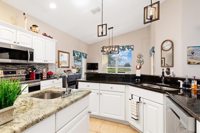 kitchen featuring sink, decorative light fixtures, dark stone counters, stainless steel appliances, and white cabinets