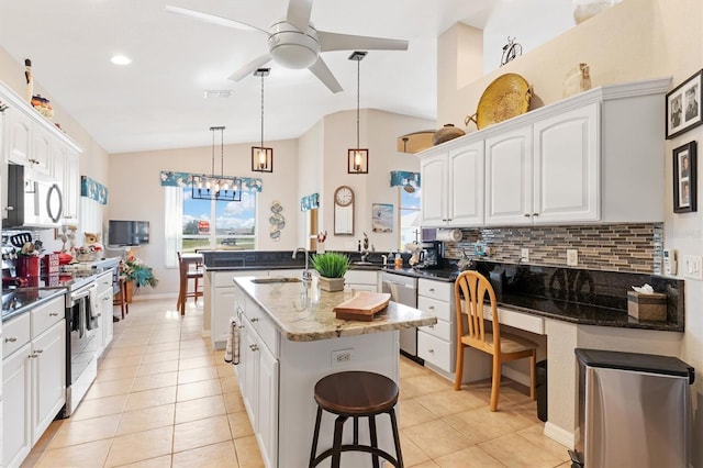 kitchen with appliances with stainless steel finishes, white cabinetry, an island with sink, sink, and dark stone counters